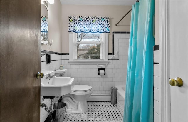 bathroom with tile walls, a baseboard radiator, toilet, shower / bath combo with shower curtain, and a sink