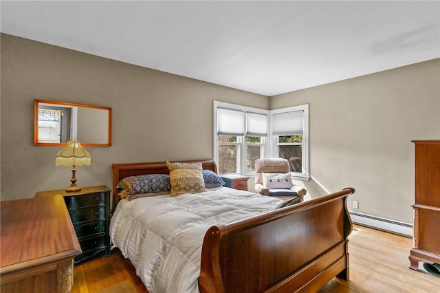 bedroom featuring light wood finished floors and baseboard heating