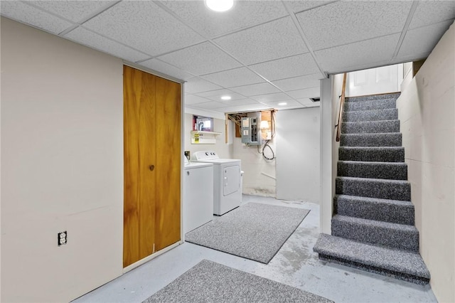 basement featuring concrete block wall, electric panel, stairway, independent washer and dryer, and a paneled ceiling