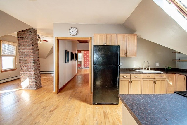 kitchen with lofted ceiling, light wood-style flooring, freestanding refrigerator, light brown cabinets, and a sink