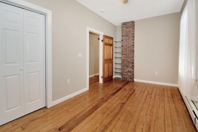 unfurnished bedroom featuring light wood finished floors, baseboards, and a baseboard heating unit