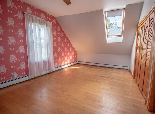 additional living space featuring lofted ceiling, ceiling fan, light wood finished floors, and wallpapered walls