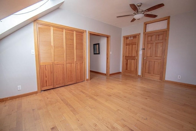 unfurnished bedroom featuring light wood finished floors, a skylight, a ceiling fan, and baseboards