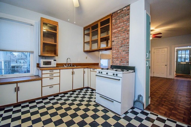 kitchen with dark floors, white cabinets, a sink, ceiling fan, and white appliances