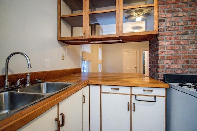 kitchen featuring butcher block counters, a sink, white cabinetry, a ceiling fan, and gas range gas stove