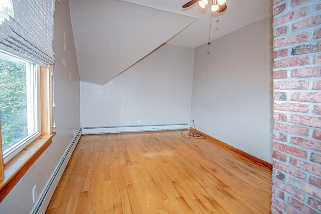 unfurnished room featuring lofted ceiling, a baseboard radiator, baseboards, light wood-style floors, and baseboard heating