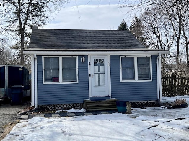 bungalow with a shingled roof, entry steps, and a chimney