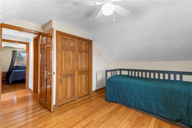 bedroom featuring a ceiling fan, light wood-type flooring, baseboards, and vaulted ceiling