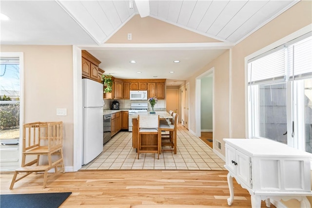 kitchen featuring a wealth of natural light, white appliances, a kitchen island, and vaulted ceiling