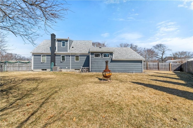 back of property featuring a yard, a fenced backyard, roof with shingles, and a chimney