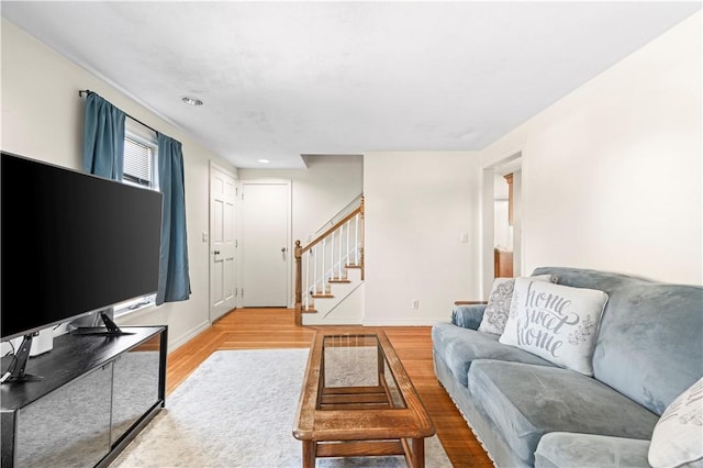 living room with stairs, baseboards, and light wood finished floors