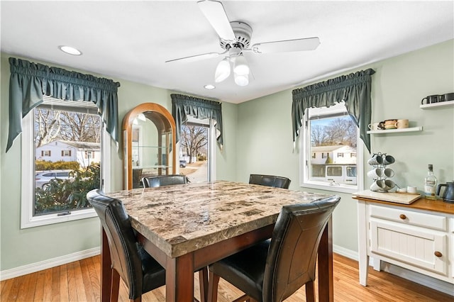 dining room featuring baseboards, plenty of natural light, a ceiling fan, and light wood finished floors