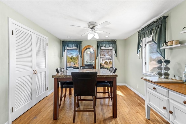 dining area with baseboards, light wood-style floors, and a ceiling fan