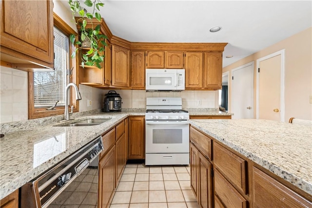 kitchen featuring a sink, light stone counters, tasteful backsplash, white appliances, and brown cabinetry