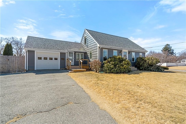 view of front of home featuring an attached garage, driveway, roof with shingles, and fence