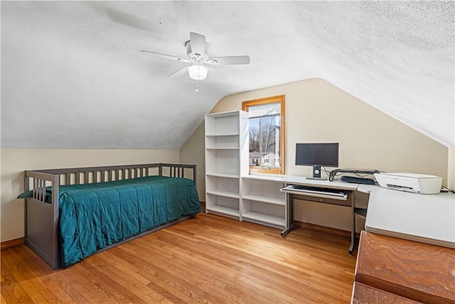 bedroom featuring a ceiling fan, vaulted ceiling, wood finished floors, and a textured ceiling