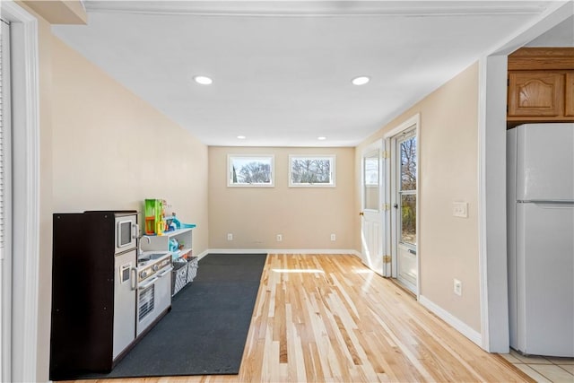 interior space with light wood finished floors, recessed lighting, baseboards, and freestanding refrigerator