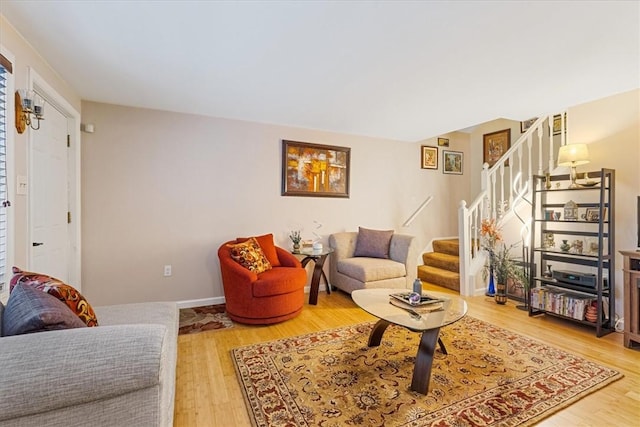 living room featuring baseboards, stairway, and wood finished floors