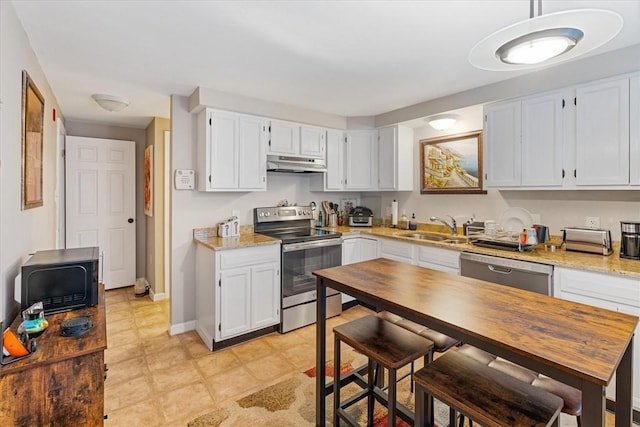 kitchen featuring baseboards, appliances with stainless steel finishes, under cabinet range hood, white cabinetry, and a sink