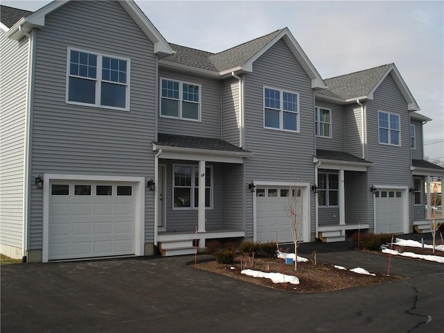 view of front facade featuring a garage, a shingled roof, and aphalt driveway