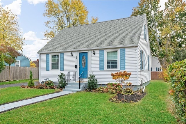 view of front of house featuring a front lawn, roof with shingles, and fence