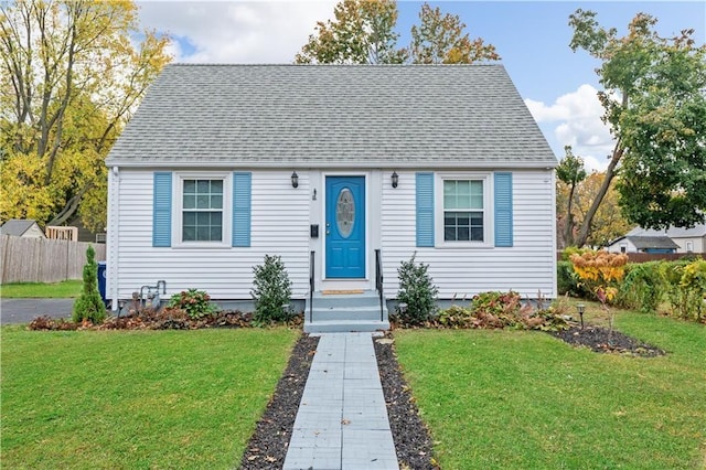 bungalow-style house with entry steps, roof with shingles, and a front yard