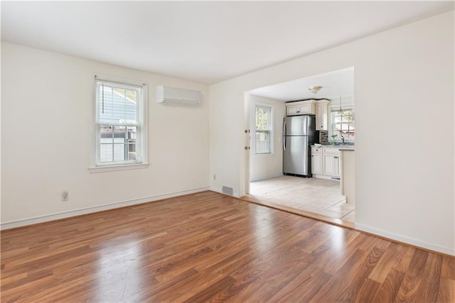 interior space featuring light wood-style floors, a healthy amount of sunlight, a sink, and a wall mounted AC