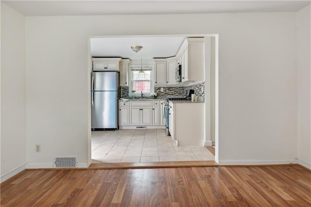 kitchen with light wood finished floors, white cabinetry, appliances with stainless steel finishes, and a sink