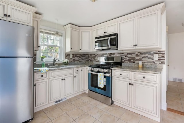 kitchen with appliances with stainless steel finishes, visible vents, a sink, and backsplash