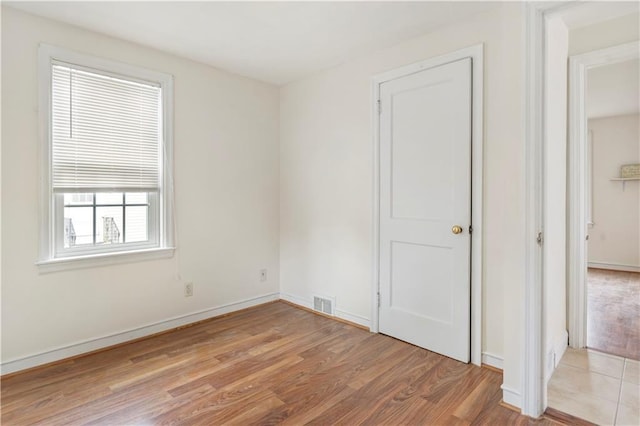 unfurnished room with baseboards, visible vents, and light wood-style floors