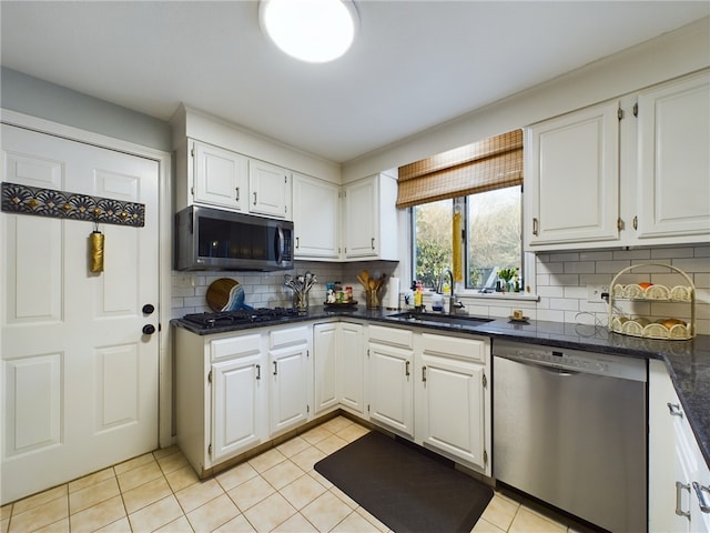 kitchen featuring appliances with stainless steel finishes, a sink, white cabinetry, and tasteful backsplash