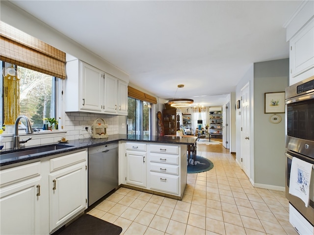 kitchen featuring stainless steel appliances, a peninsula, a sink, and white cabinetry