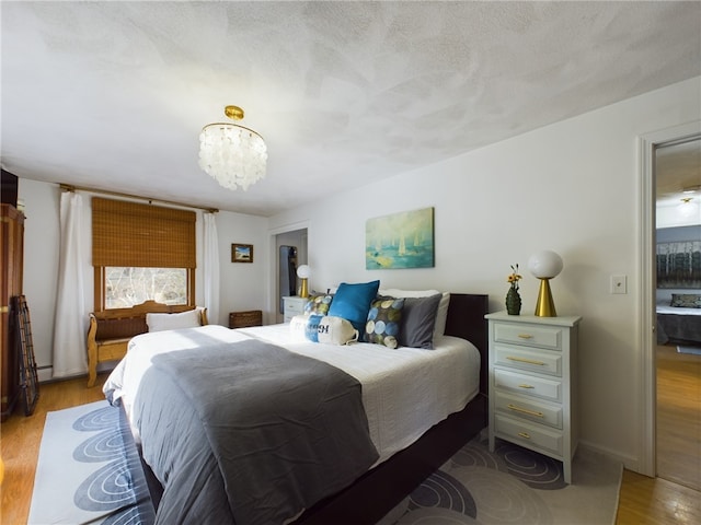 bedroom featuring a textured ceiling, light wood finished floors, and a notable chandelier