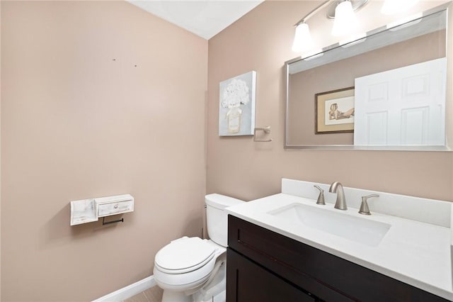 bathroom with toilet, baseboards, and vanity