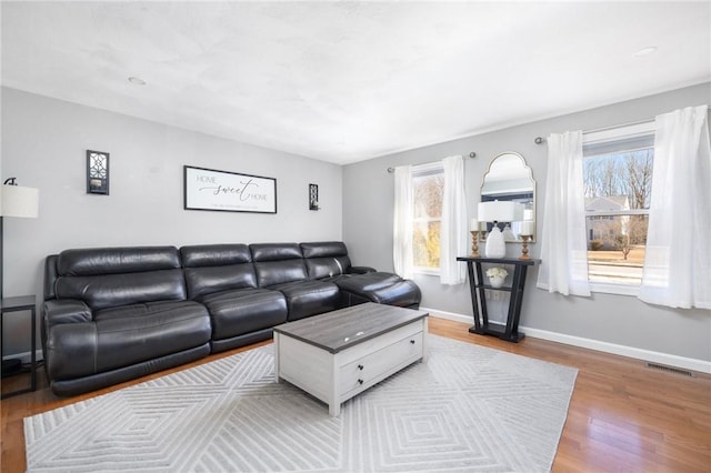 living room with baseboards, visible vents, a wealth of natural light, and wood finished floors