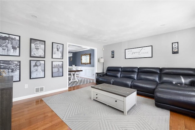 living room with wainscoting, wood finished floors, and visible vents