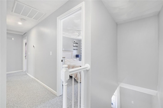 corridor with baseboards, visible vents, and carpet flooring