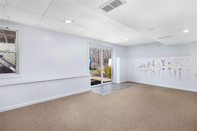 carpeted spare room featuring a paneled ceiling, baseboards, and visible vents