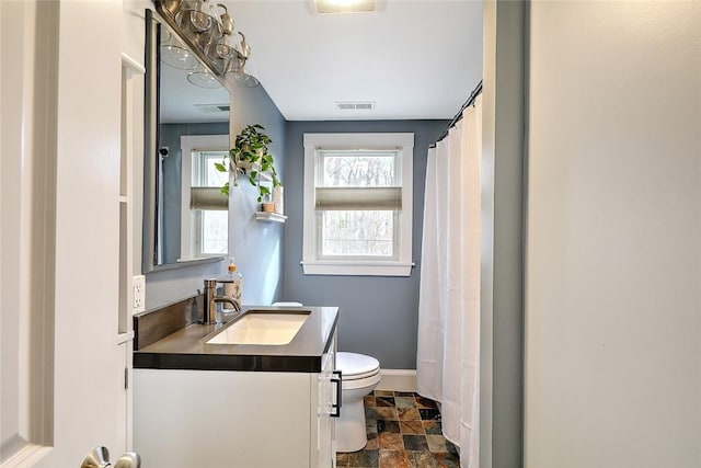 full bath featuring visible vents, toilet, stone finish floor, vanity, and baseboards