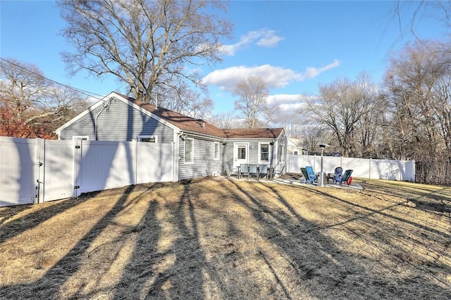 back of property with a fenced backyard, a gate, and a patio