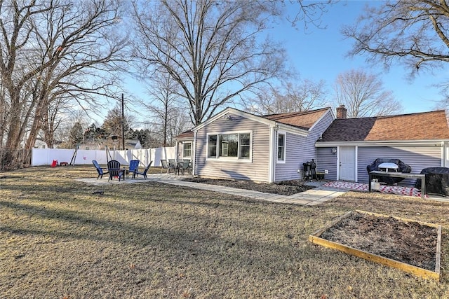 exterior space featuring a shingled roof, a chimney, fence, a yard, and a patio area