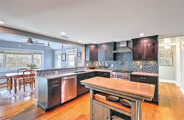 kitchen featuring wall chimney exhaust hood, tasteful backsplash, a sink, and stainless steel appliances