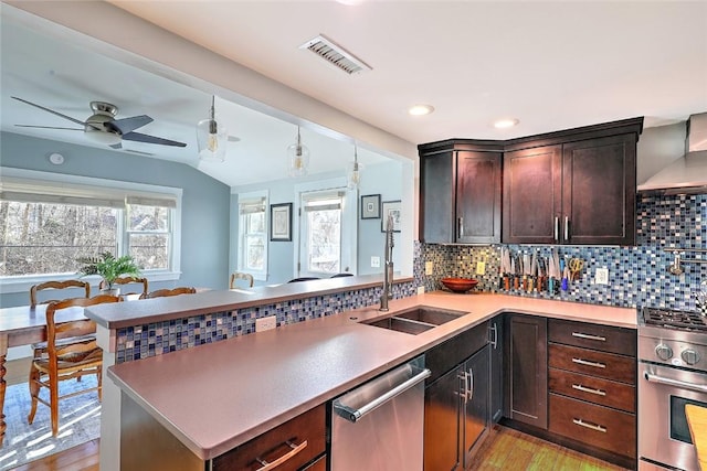 kitchen featuring tasteful backsplash, visible vents, appliances with stainless steel finishes, a sink, and a peninsula