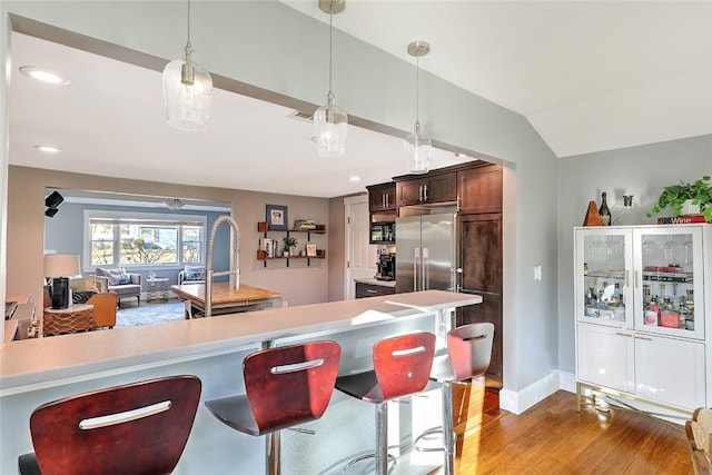 kitchen with light countertops, decorative light fixtures, a kitchen breakfast bar, and wood finished floors