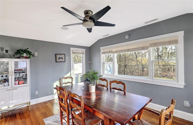 dining area featuring visible vents, vaulted ceiling, baseboards, and wood finished floors