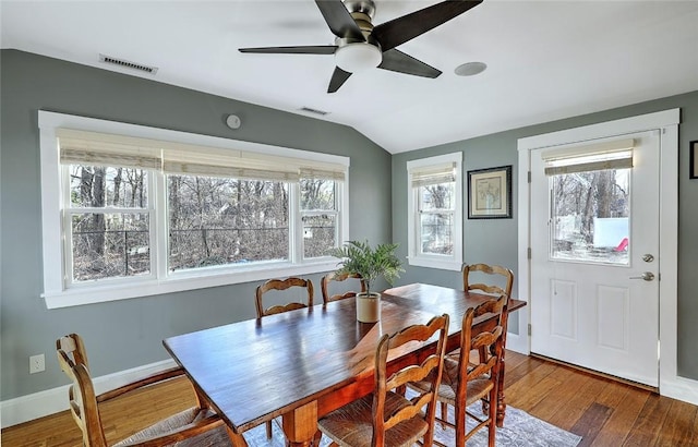 dining space featuring a healthy amount of sunlight, visible vents, vaulted ceiling, and hardwood / wood-style floors