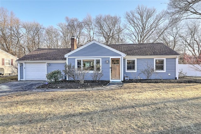 ranch-style house with a garage, roof with shingles, driveway, and a chimney