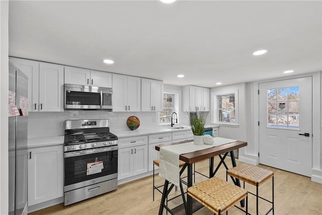 kitchen with stainless steel appliances, light countertops, a sink, and white cabinetry