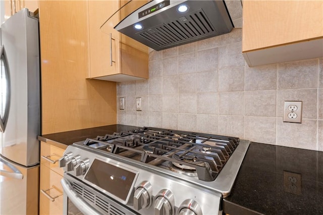 kitchen featuring light brown cabinets, wall chimney range hood, appliances with stainless steel finishes, decorative backsplash, and dark countertops