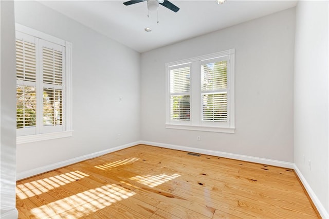 unfurnished room featuring a ceiling fan, a healthy amount of sunlight, baseboards, and wood finished floors